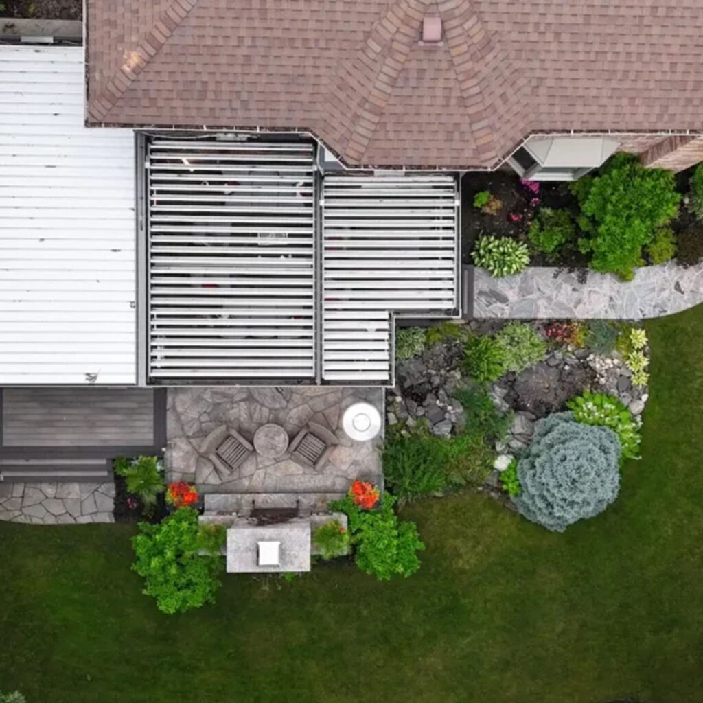 Aerial view of a modern backyard with a pergola-covered deck, stone patio, outdoor seating area, and landscaped garden – project by The Deck Store.